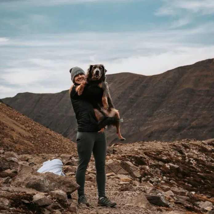 Melissa, Pet First Aid instructor at PAWS Dog Daycare, holding a dog on a Rocky Mountain trail